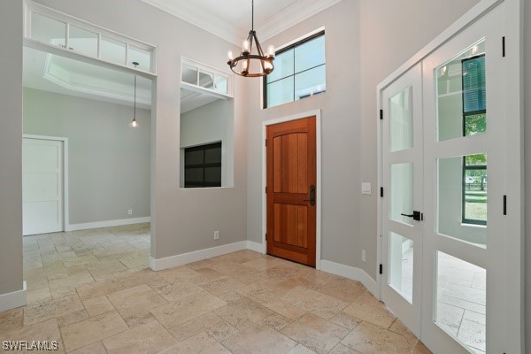 4740 5th Ave SW, Naples, FL 34119 - foyer entrance with stone tile flooring, a chandelier, a towering ceiling, and crown molding
