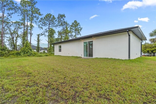 311 Long Ave S, Lehigh Acres, FL 33974 - back of property featuring stucco siding and a yard
