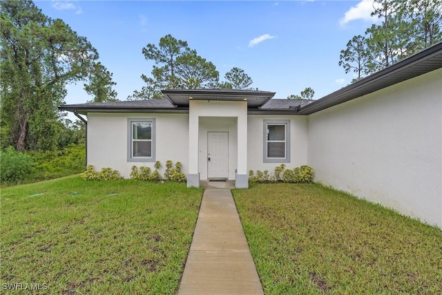 311 Long Ave S, Lehigh Acres, FL 33974 - view of front of home featuring stucco siding and a front lawn