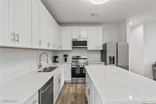 311 Long Ave S, Lehigh Acres, FL 33974 - kitchen with appliances with stainless steel finishes, a kitchen island, wood finished floors, white cabinets, and light stone countertops
