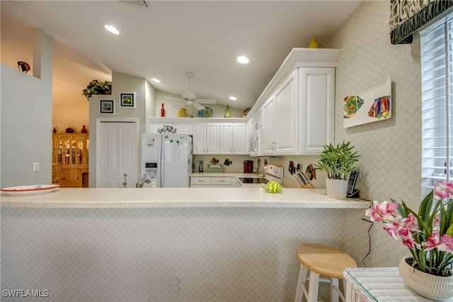 17791 Pineapple Palm Ct, North Fort Myers, FL 33917 - kitchen with white appliances, light countertops, a ceiling fan, vaulted ceiling, and a kitchen breakfast bar