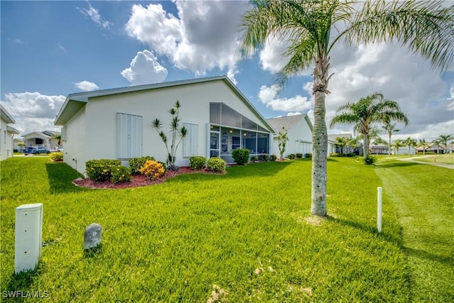 17791 Pineapple Palm Ct, North Fort Myers, FL 33917 - view of side of home with stucco siding, a yard, and a sunroom