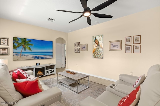 12905 Pastures Way, Fort Myers, FL 33913 - living area featuring arched walkways, a ceiling fan, tile patterned flooring, and a warm lit fireplace