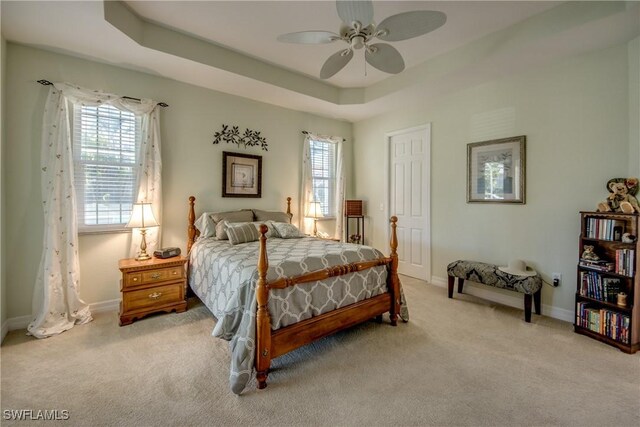 2102 SW 47th St, Cape Coral, FL 33914 - carpeted bedroom featuring multiple windows, a tray ceiling, and a ceiling fan