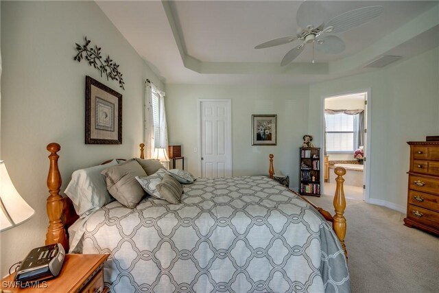 2102 SW 47th St, Cape Coral, FL 33914 - bedroom featuring light colored carpet, a tray ceiling, connected bathroom, and ceiling fan