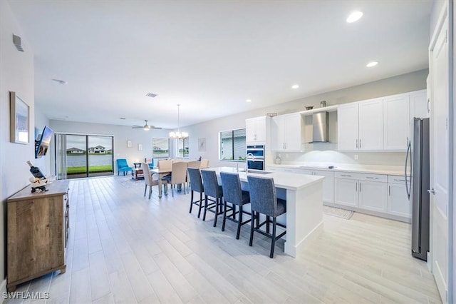 4955 Brigata Way, Ave Maria, FL 34142 - kitchen featuring appliances with stainless steel finishes, wall chimney range hood, light wood-type flooring, light countertops, and recessed lighting