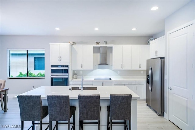 4955 Brigata Way, Ave Maria, FL 34142 - kitchen with appliances with stainless steel finishes, wall chimney exhaust hood, a kitchen breakfast bar, light wood finished floors, and recessed lighting