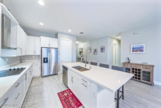 4955 Brigata Way, Ave Maria, FL 34142 - kitchen featuring appliances with stainless steel finishes, a kitchen bar, light wood-type flooring, white cabinets, and recessed lighting