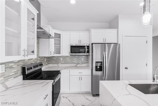 7029 Palpano Cir, Labelle, FL 33935 - kitchen with stainless steel appliances, white cabinets, glass insert cabinets, wall chimney exhaust hood, and light marble finish flooring