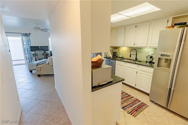 3052 Kings Lake Blvd Unit 7554, Naples, FL 34112 - kitchen featuring appliances with stainless steel finishes, light tile patterned floors, dark stone counters, tasteful backsplash, and white cabinetry