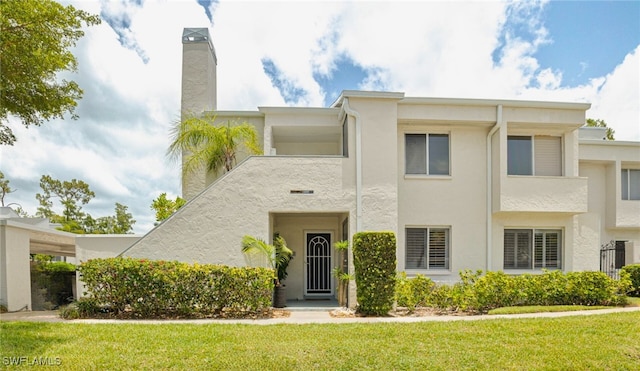 3052 Kings Lake Blvd Unit 7554, Naples, FL 34112 - view of front facade featuring stucco siding, a front yard, and a chimney