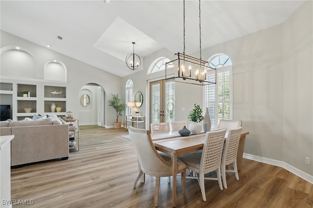 12006 Cypress Links Dr, Fort Myers, FL 33913 - dining area featuring arched walkways, a chandelier, light wood-style floors, french doors, and vaulted ceiling