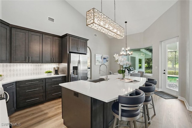 12006 Cypress Links Dr, Fort Myers, FL 33913 - kitchen with stainless steel fridge, high vaulted ceiling, a chandelier, light wood-type flooring, and backsplash