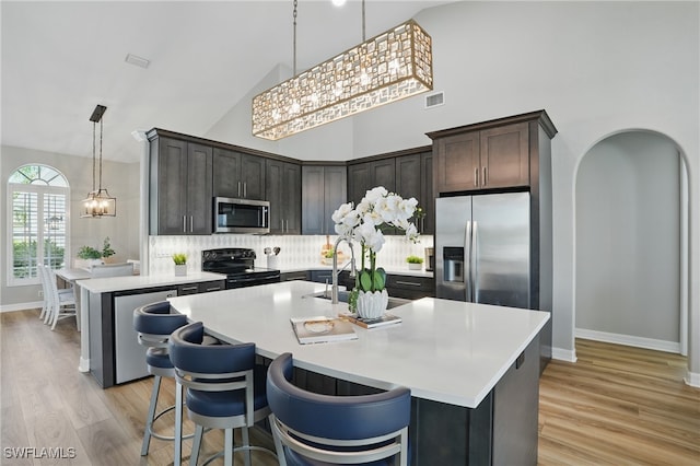 12006 Cypress Links Dr, Fort Myers, FL 33913 - kitchen with stainless steel appliances, a chandelier, high vaulted ceiling, backsplash, and light countertops