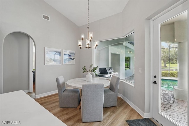 12006 Cypress Links Dr, Fort Myers, FL 33913 - dining room featuring a chandelier, light wood-style floors, arched walkways, and high vaulted ceiling