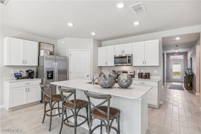 2982 Ernest Way, Fort Myers, FL 33905 - kitchen featuring appliances with stainless steel finishes, light wood-style floors, an island with sink, white cabinetry, and recessed lighting