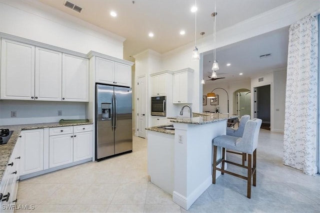 29120 Brendisi Way Unit 102, Naples, FL 34110 - kitchen featuring appliances with stainless steel finishes, light stone counters, pendant lighting, a breakfast bar, and white cabinetry
