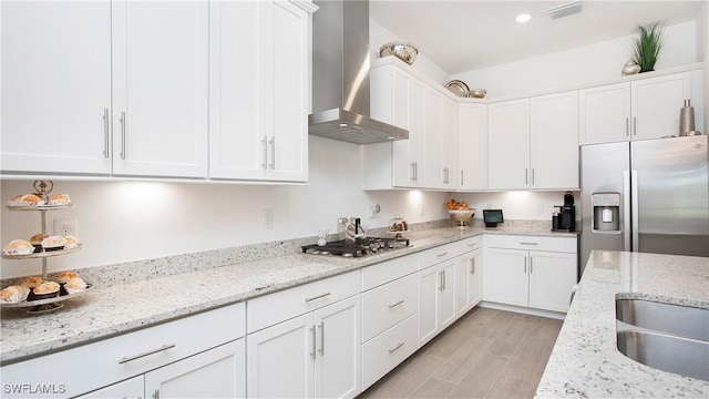 15898 Sugar Hill Dr, Punta Gorda, FL 33982 - kitchen featuring wall chimney exhaust hood, stainless steel appliances, white cabinetry, light wood-style flooring, and light stone counters