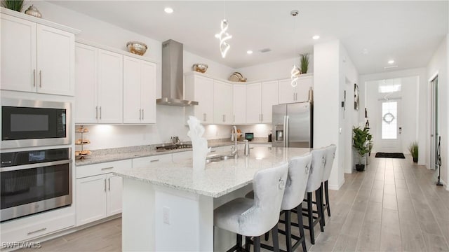 15898 Sugar Hill Dr, Punta Gorda, FL 33982 - kitchen with stainless steel appliances, wall chimney exhaust hood, white cabinetry, a breakfast bar, and light stone counters
