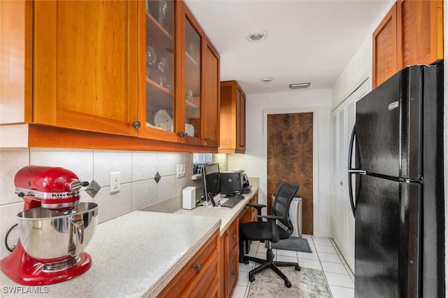 24398 Treasure Island Blvd, Punta Gorda, FL 33955 - kitchen with freestanding refrigerator, built in study area, light countertops, brown cabinets, and glass insert cabinets