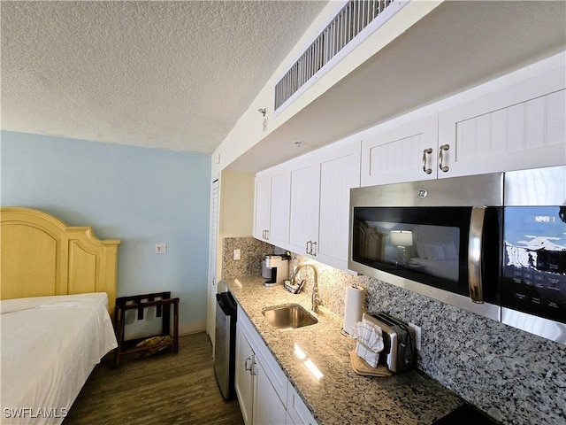 140 Estero Blvd Unit 2206, Fort Myers Beach, FL 33931 - kitchen with appliances with stainless steel finishes, dark wood-type flooring, light stone countertops, a textured ceiling, and white cabinetry