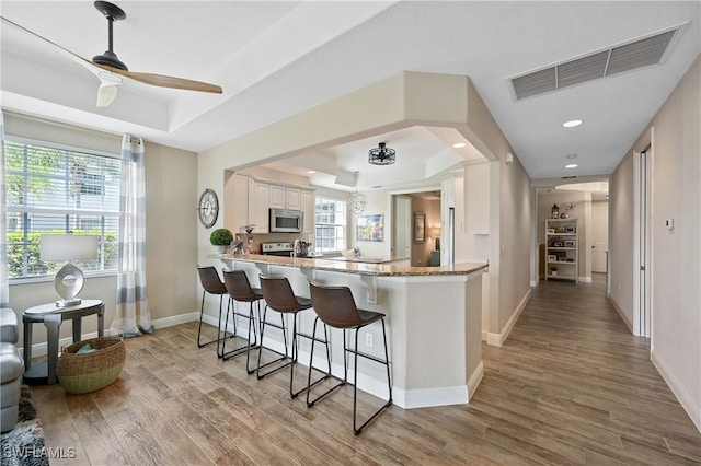19671 Marino Lake Cir Unit 1602, Miromar Lakes, FL 33913 - kitchen with a tray ceiling, light wood-type flooring, a ceiling fan, a breakfast bar area, and recessed lighting