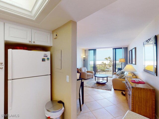 58 N Collier Blvd Unit 404, Marco Island, FL 34145 - kitchen with freestanding refrigerator, white cabinetry, healthy amount of natural light, light tile patterned floors, and expansive windows