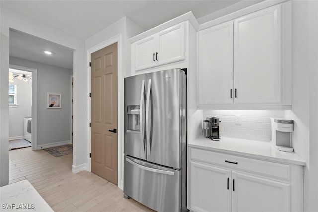 10581 Woodchuck Ln, Bonita Springs, FL 34135 - kitchen featuring stainless steel refrigerator with ice dispenser, white cabinetry, light countertops, decorative backsplash, and light wood-style flooring