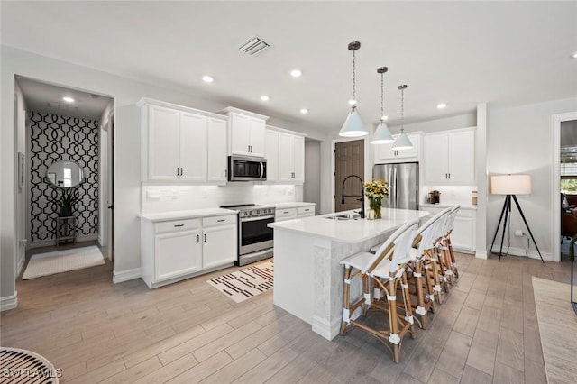 10581 Woodchuck Ln, Bonita Springs, FL 34135 - kitchen with stainless steel appliances, backsplash, a kitchen island with sink, light wood-style floors, and recessed lighting