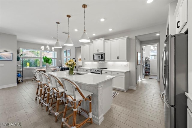 10581 Woodchuck Ln, Bonita Springs, FL 34135 - kitchen with stainless steel appliances, light countertops, a breakfast bar, a kitchen island with sink, and backsplash