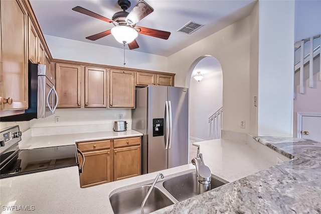 10058 Pacific Pines Ave, Fort Myers, FL 33966 - kitchen featuring appliances with stainless steel finishes, ceiling fan, arched walkways, and brown cabinetry
