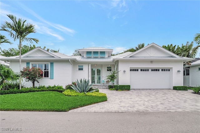 2120 Curtis St, Naples, FL 34112 - ranch-style home with french doors, an attached garage, decorative driveway, a front lawn, and a metal roof