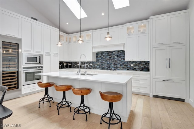 2120 Curtis St, Naples, FL 34112 - kitchen featuring stainless steel appliances, a skylight, wine cooler, a breakfast bar area, and tasteful backsplash