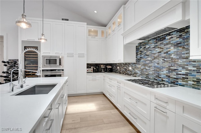 2120 Curtis St, Naples, FL 34112 - kitchen featuring stainless steel appliances, lofted ceiling, custom exhaust hood, light wood-style floors, and white cabinetry