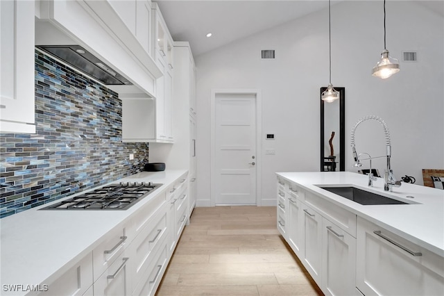 2120 Curtis St, Naples, FL 34112 - kitchen with stainless steel gas cooktop, decorative backsplash, light wood-style floors, light countertops, and white cabinetry