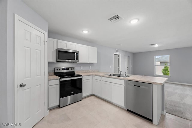 2816 27th St SW, Lehigh Acres, FL 33976 - kitchen with stainless steel appliances, a peninsula, light countertops, white cabinets, and recessed lighting