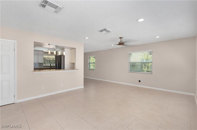 1141 S Alhambra Cir, Naples, FL 34103 - empty room featuring a ceiling fan, plenty of natural light, a textured ceiling, recessed lighting, and light tile patterned flooring