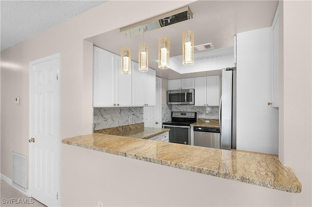 1141 S Alhambra Cir, Naples, FL 34103 - kitchen featuring stainless steel appliances, decorative backsplash, white cabinetry, a peninsula, and pendant lighting