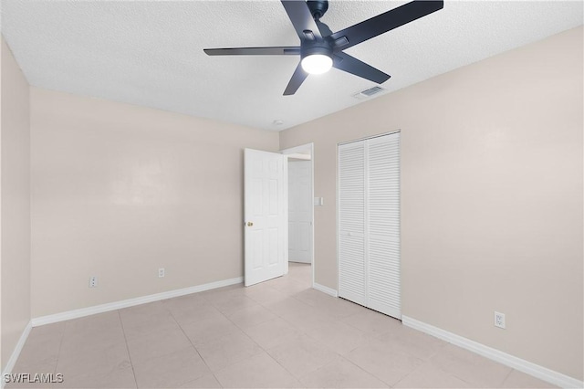 1141 S Alhambra Cir, Naples, FL 34103 - unfurnished bedroom with a textured ceiling, a closet, ceiling fan, and light tile patterned flooring