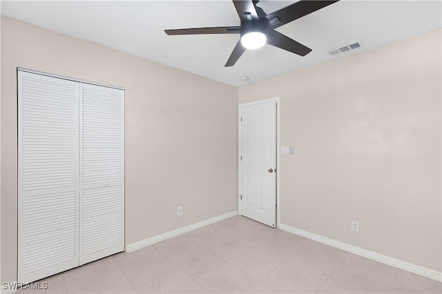 1141 S Alhambra Cir, Naples, FL 34103 - unfurnished bedroom with a closet, a textured ceiling, a ceiling fan, and light tile patterned floors