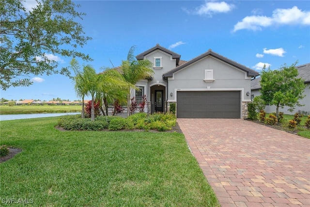 2703 Aviamar Cir, Naples, FL 34114 - view of front of house with stucco siding, a front lawn, decorative driveway, an attached garage, and a water view
