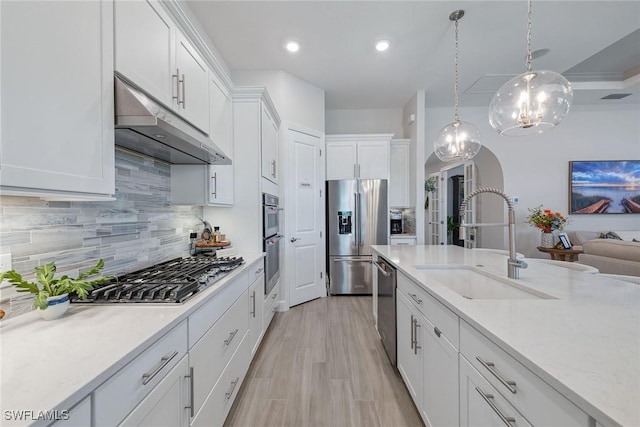 2703 Aviamar Cir, Naples, FL 34114 - kitchen with stainless steel appliances, under cabinet range hood, arched walkways, white cabinets, and backsplash