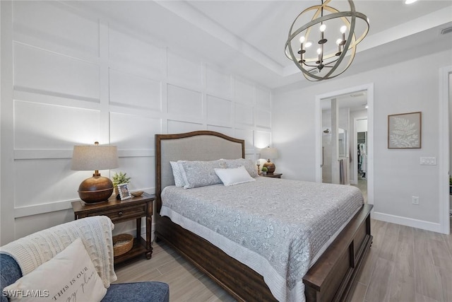2703 Aviamar Cir, Naples, FL 34114 - bedroom with a chandelier, light wood-style floors, and a tray ceiling