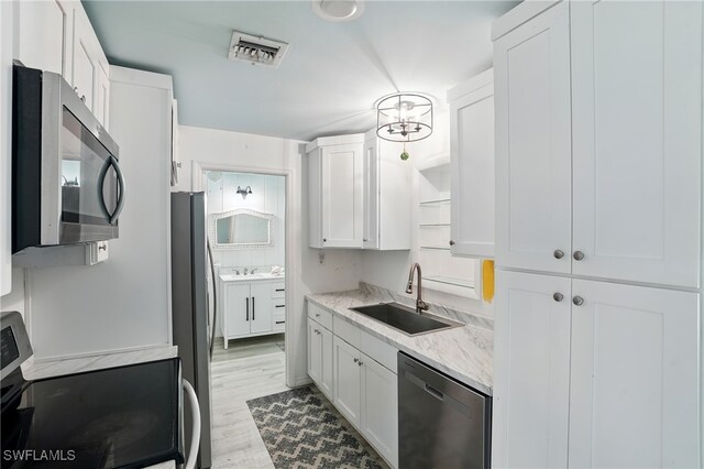4011 Coconut Cir S, Naples, FL 34104 - kitchen with stainless steel appliances, white cabinetry, light wood-style floors, and light stone countertops