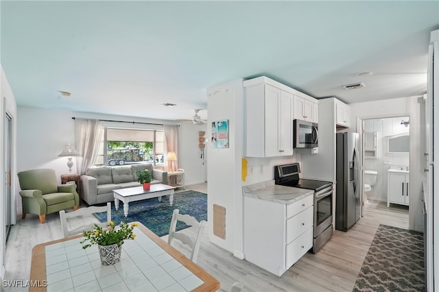 4011 Coconut Cir S, Naples, FL 34104 - kitchen featuring appliances with stainless steel finishes, open floor plan, light wood finished floors, and a ceiling fan