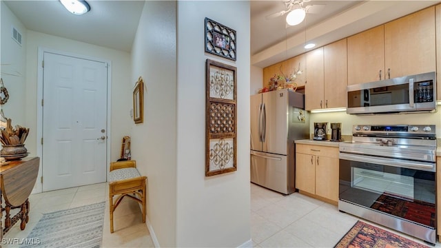 1133 Van Loon Commons Cir Unit 202, Cape Coral, FL 33909 - kitchen featuring appliances with stainless steel finishes, light tile patterned floors, light brown cabinetry, light countertops, and ceiling fan