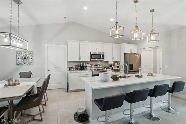 1028 NW 33rd Ave, Cape Coral, FL 33993 - kitchen featuring appliances with stainless steel finishes, lofted ceiling, a breakfast bar area, white cabinetry, and an island with sink