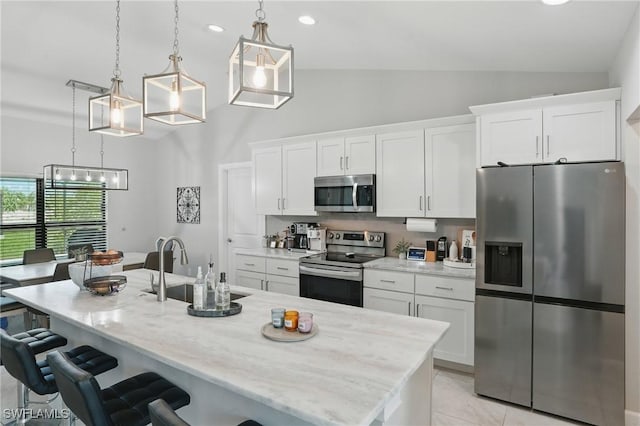 1028 NW 33rd Ave, Cape Coral, FL 33993 - kitchen featuring appliances with stainless steel finishes, white cabinetry, a kitchen breakfast bar, an island with sink, and decorative light fixtures