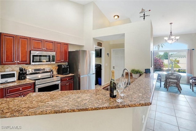 2127 SW 49th Ter, Cape Coral, FL 33914 - kitchen featuring appliances with stainless steel finishes, light stone counters, a chandelier, and tasteful backsplash