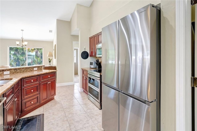 2127 SW 49th Ter, Cape Coral, FL 33914 - kitchen featuring stainless steel appliances, reddish brown cabinets, a chandelier, pendant lighting, and light stone countertops